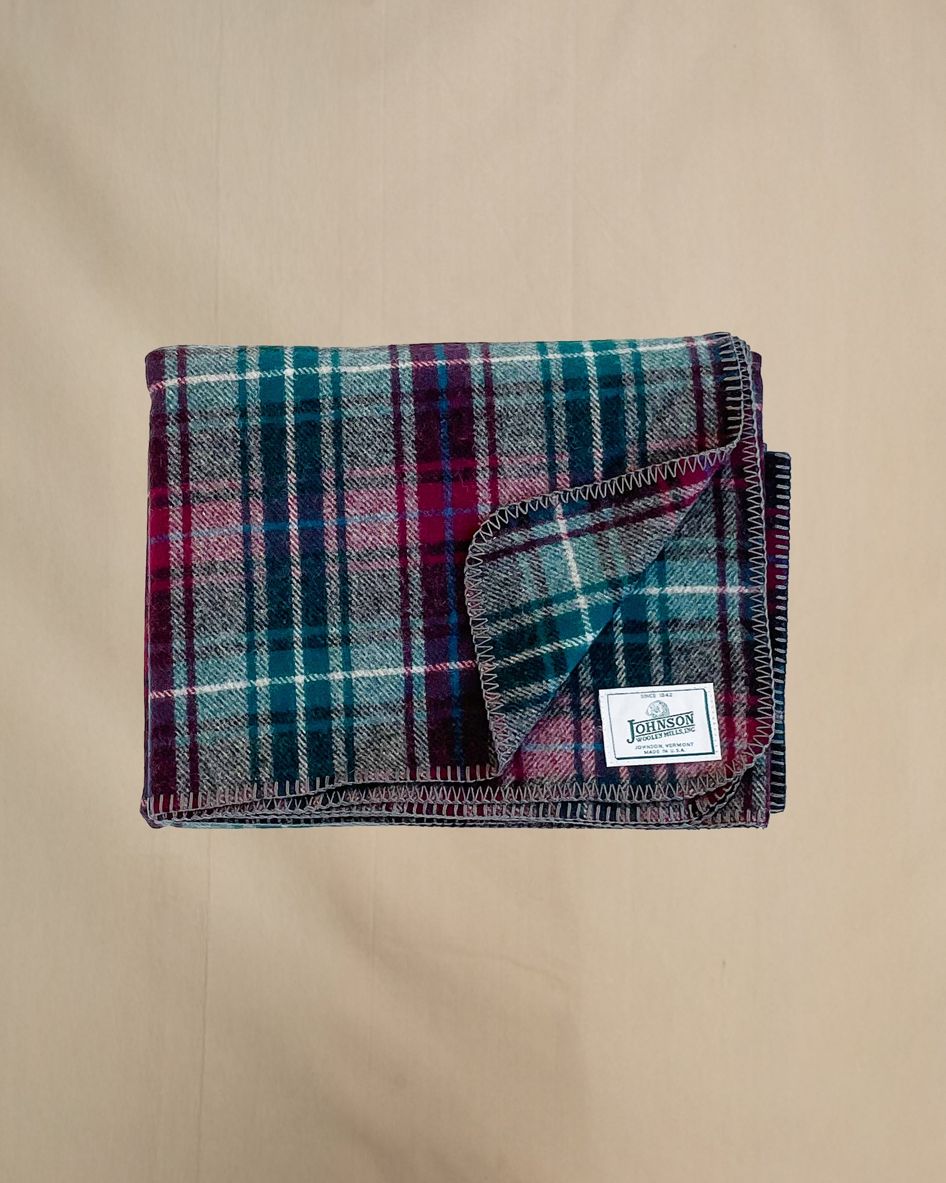 Johnson Woolen Mills Wine Gray Teel Plaid folded blanket showing logo patch