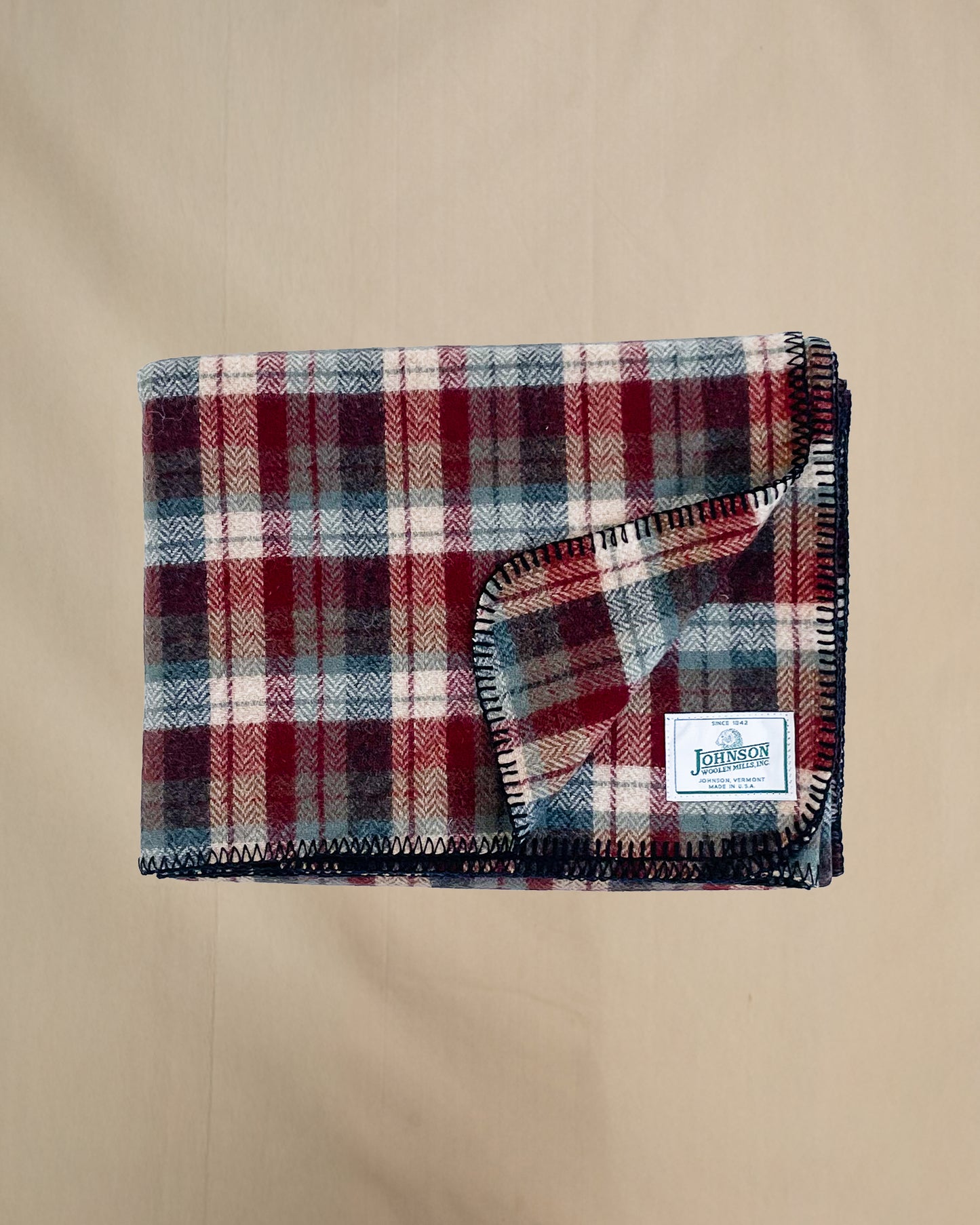 Johnson Woolen Mills Teal Rust Cream Plaid folded blanket showing logo patch
