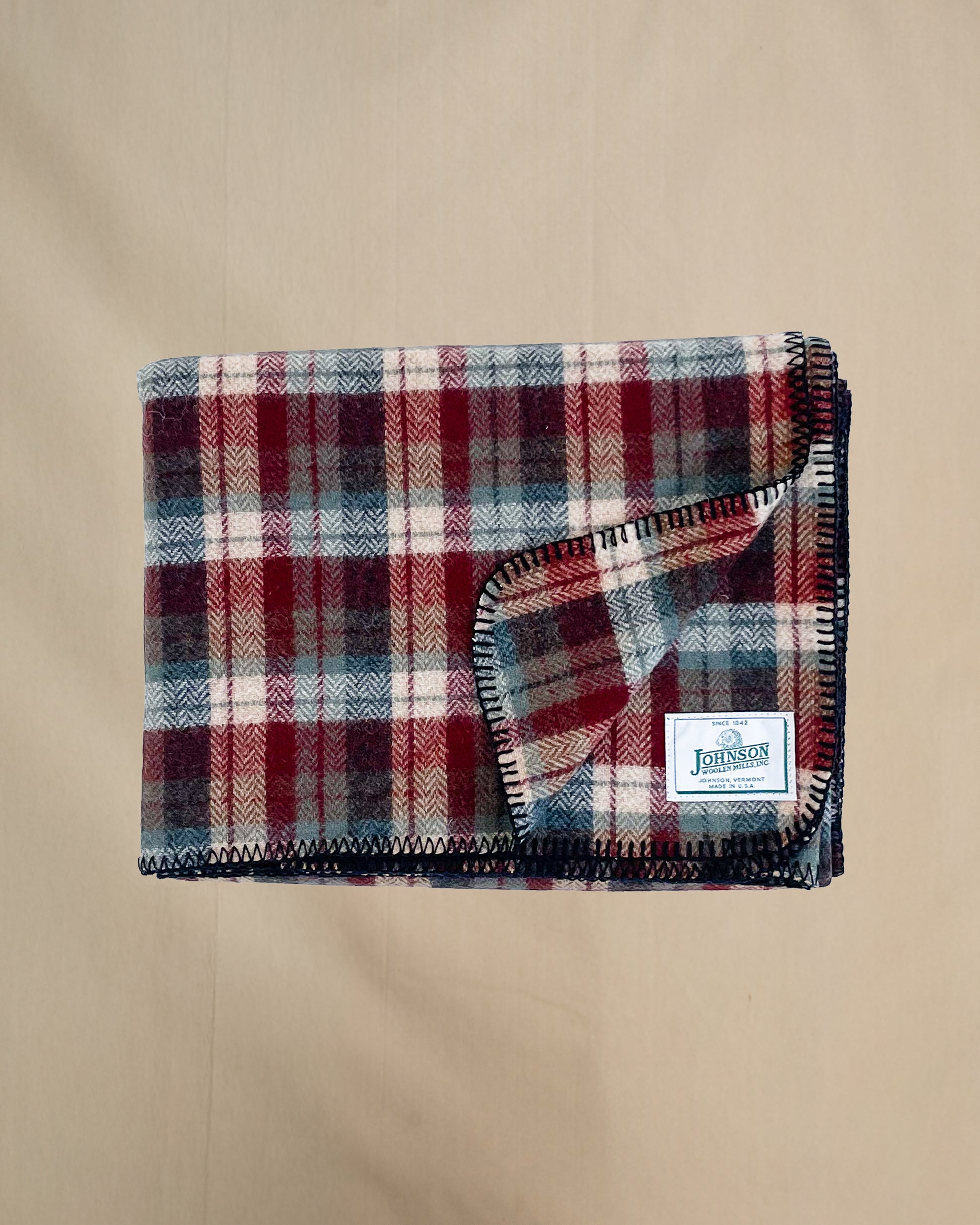 Johnson Woolen Mills Teal Rust Cream Plaid folded blanket showing logo patch