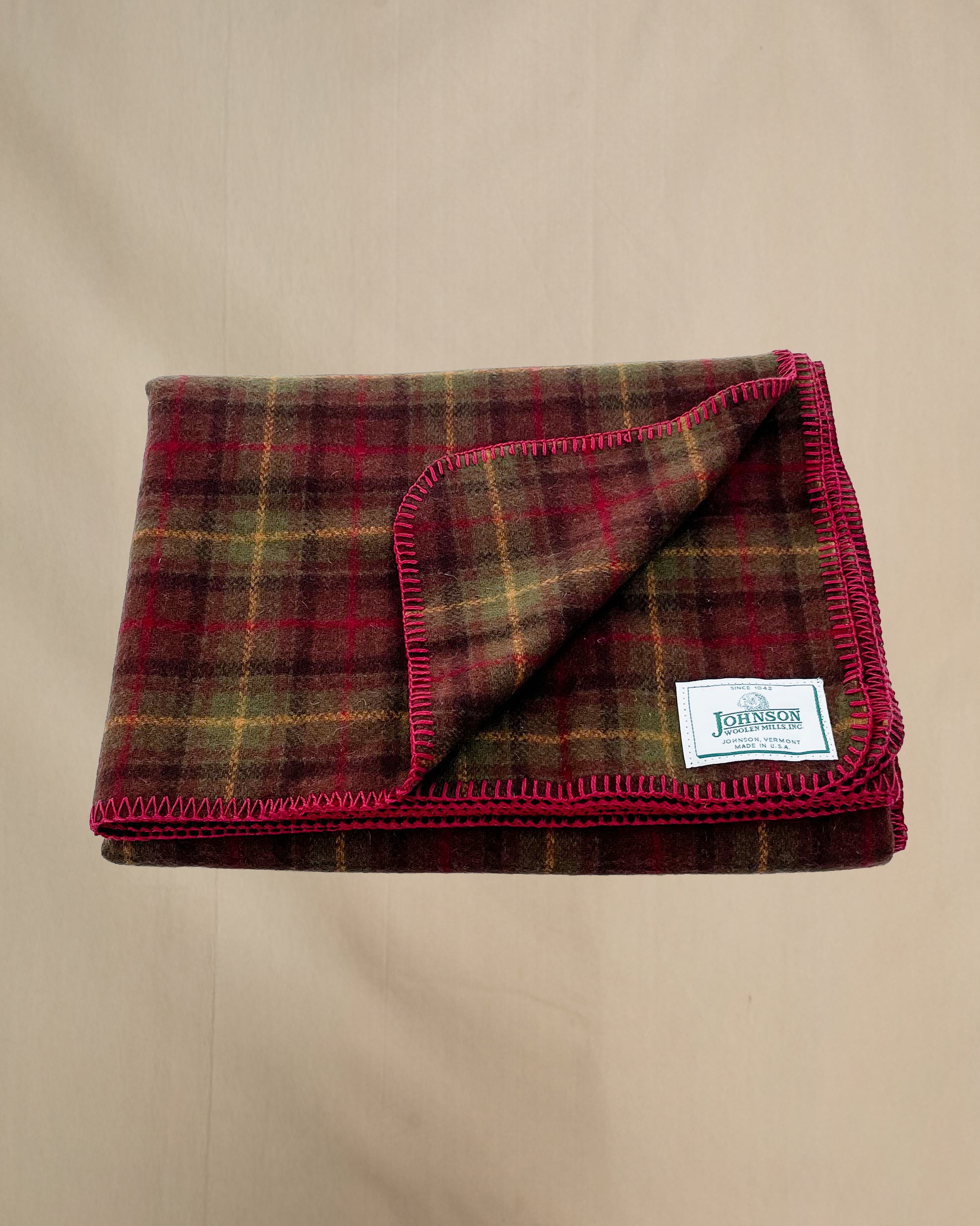 Johnson Woolen Mills throw - olive, brown, gold plaid with red stitching and logo 