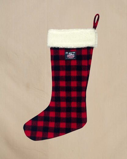 Red and black plaid Christmas stocking with white cuff on a beige background