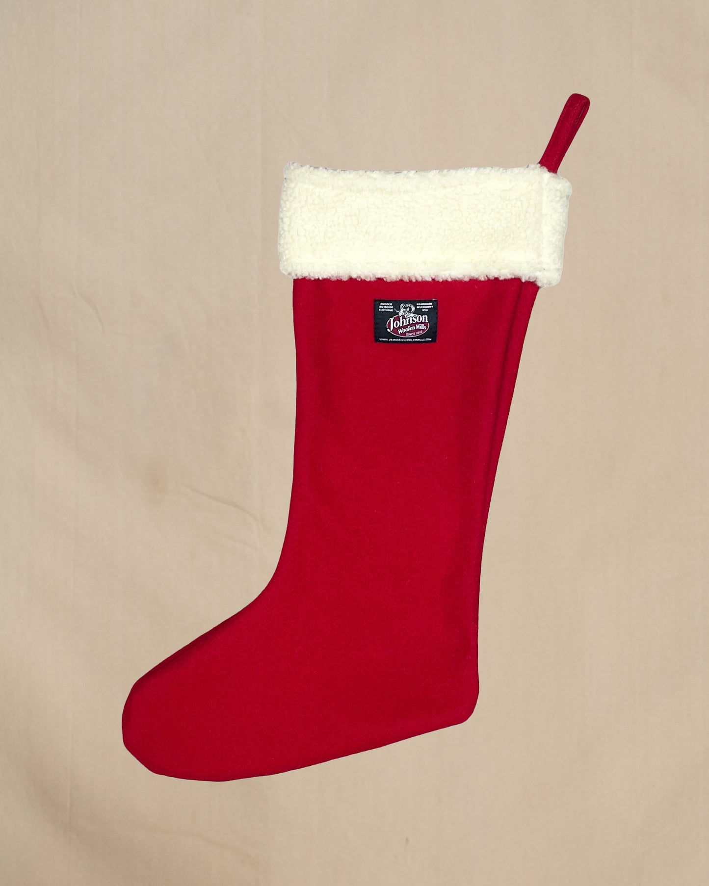 Red Christmas stocking with white fur trim on a beige background