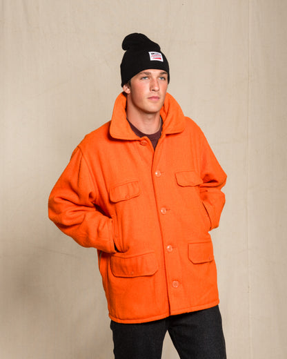 A man wearing a bright orange heavy wool vintage jacket, a black knit beanie.