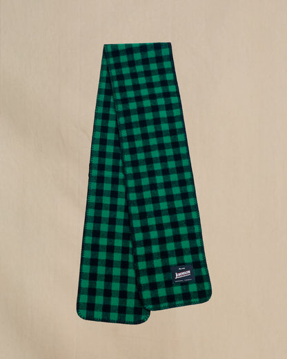 Green and black checkered scarf with a brand label on a beige background