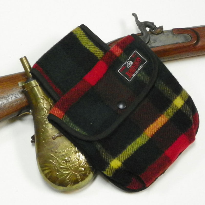 photo of green, black, red and yellow plaid black powder pouch with antique rifle 