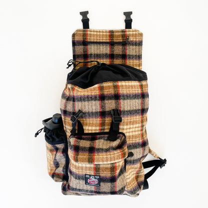 Wool back pack in gold, black and red plaid, shown with water bottle in side pocket and top flap open