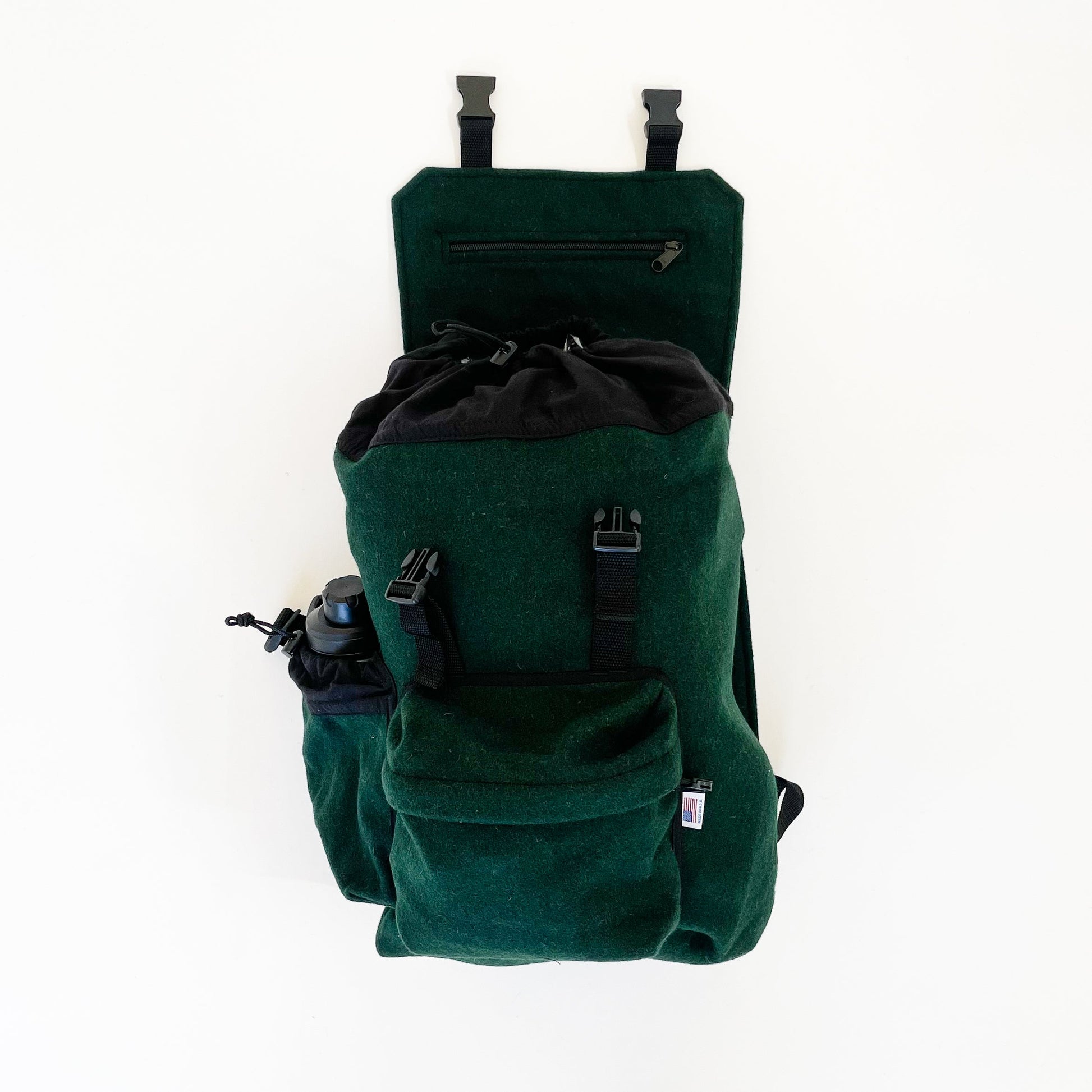 Wool back pack - Spruce green with water bottle shown in side pocket and top flap open