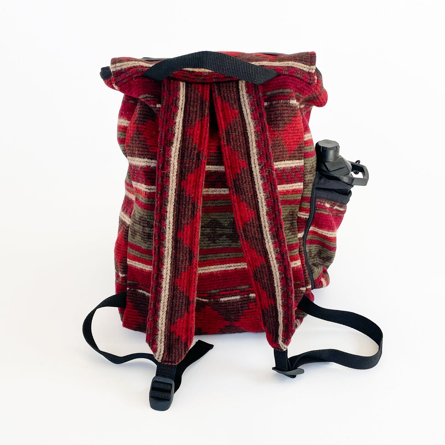 Wool back pack rust, olive and beige print, shown with water bottle in side pocket - back view